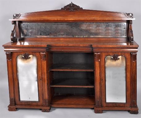 An early 19c rosewood chiffonier with a mirrored architectural backboard, with scroll carved terminals and stylistic leaf and