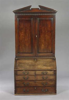 A George III Mahogany Desk and Bookcase, with a dentilled open  pediment and blind-fretted frieze over two  panelled doors en