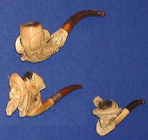 Three finely carved meerschaum cigar holders, C19th, with amber stems: one an Arab