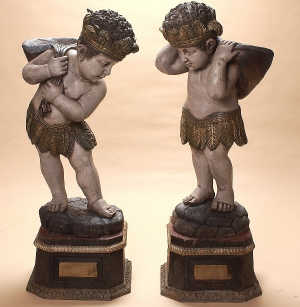 AN IMPRESSIVE PAIR OF CIGAR STORE INDIAN FIGURES, in painted and gilded wood with leafy crowns an
