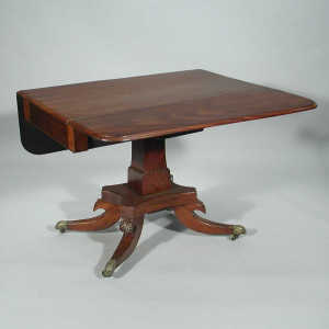 A George IV mahogany pedestal Pembroke table, with a blind frieze  drawer, on a stepped square column to four  leaf carved sw