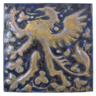 A Pilkington`s Lancastrian tile, decorated in low relief with a heraldic dragon, in copper lustre on a blue ground impressed 