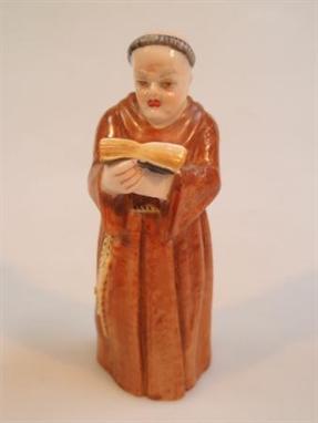 A Royal Worcester porcelain candle snuffer, modelled as a monk reading a bible, green mark and date code for 1902, 12½cm high