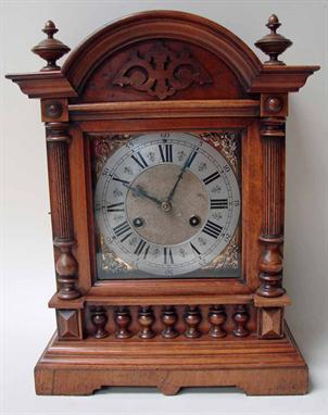 An Edwardian walnut-cased architectural style mantel clock, with brass and silvered dial, striking on the hour and half hour,