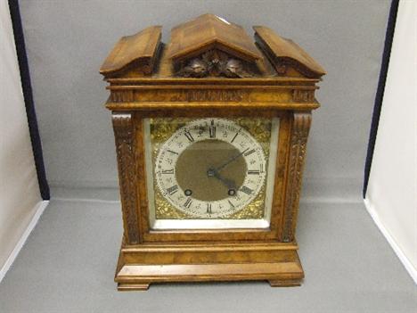 An early 20th century walnut and mahogany bracket clock having architectural pediment with spandrel face and striking German 