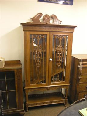 A large continental reproduction walnut display cabinet, architectural pediments above a pair of astragal-glazed doors enclos